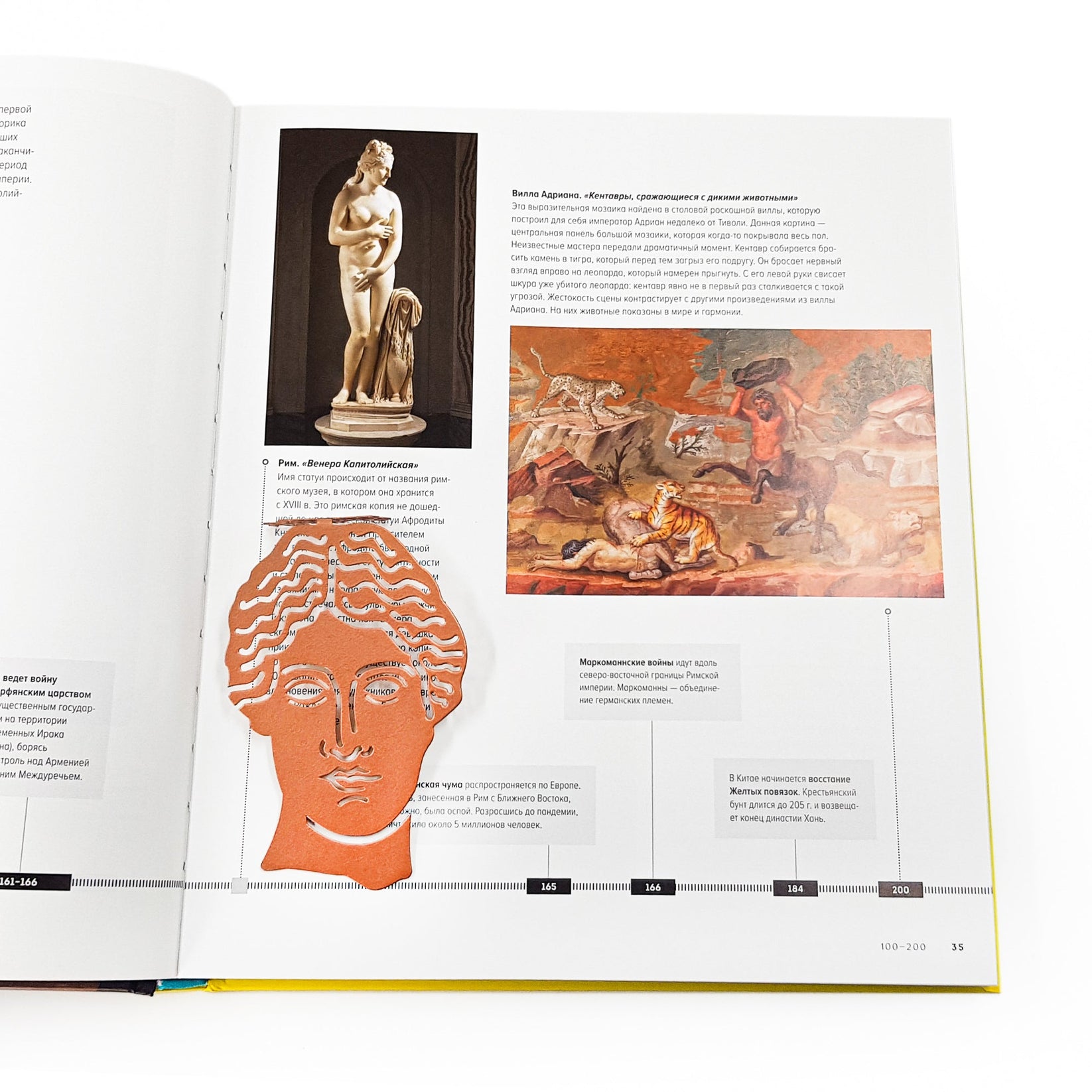 Goddess of Words metal bookmark in red marking a page in an illustrated book