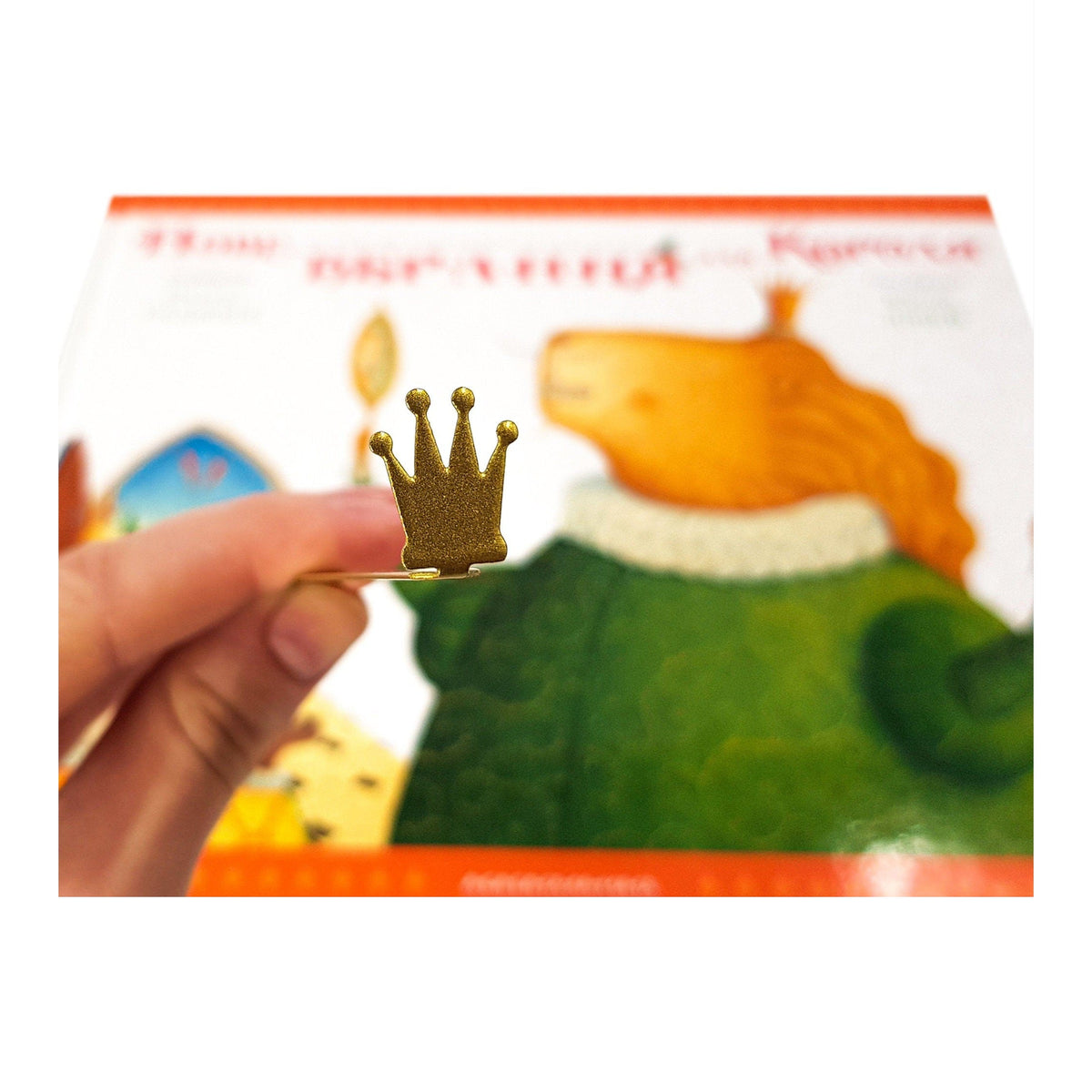 Golden Crown metal bookmark marking a page in an illustrated book
