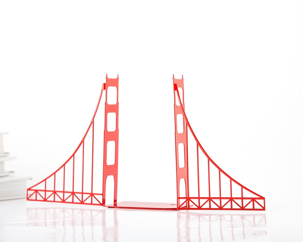 Red Golden Gate Bridge metal bookends standing on a shelf