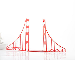 Red Golden Gate Bridge metal bookends standing on a shelf