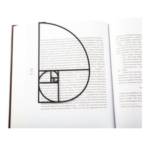 Golden Ratio metal bookmark resting on the pages of an open book