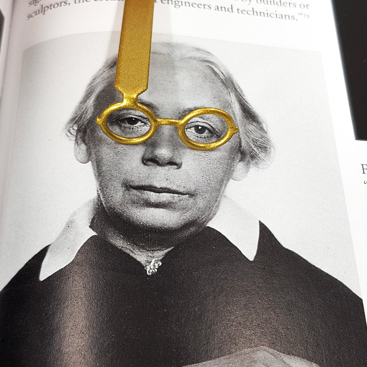Golden Round Glasses metal bookmark marking a page in an illustrated book