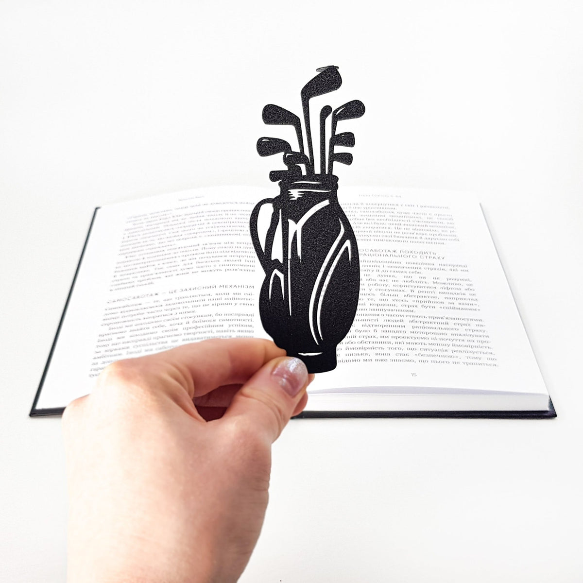 Golf Bag metal bookmark held up beside an open book