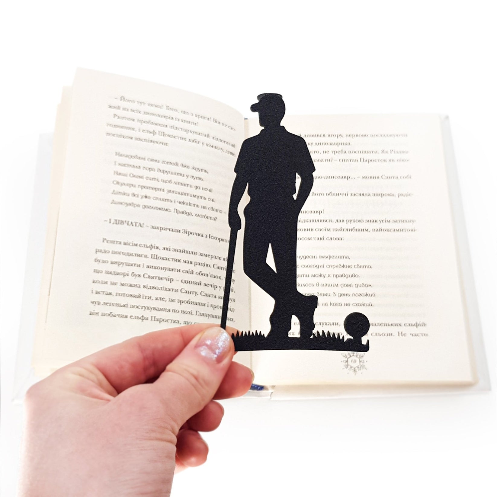 Golf Player metal bookmark held in a hand above an open book