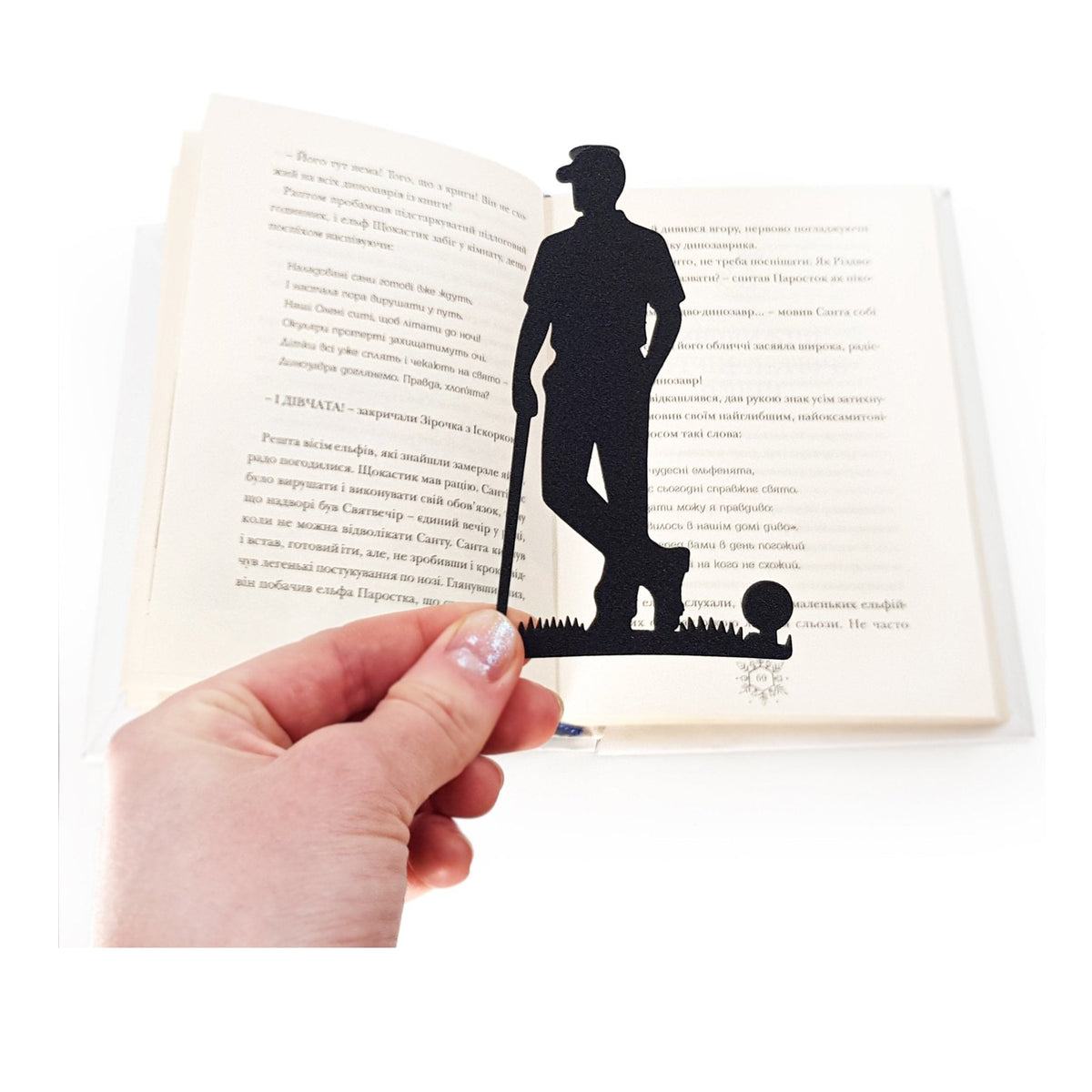 Golf Player metal bookmark held in a hand above an open book