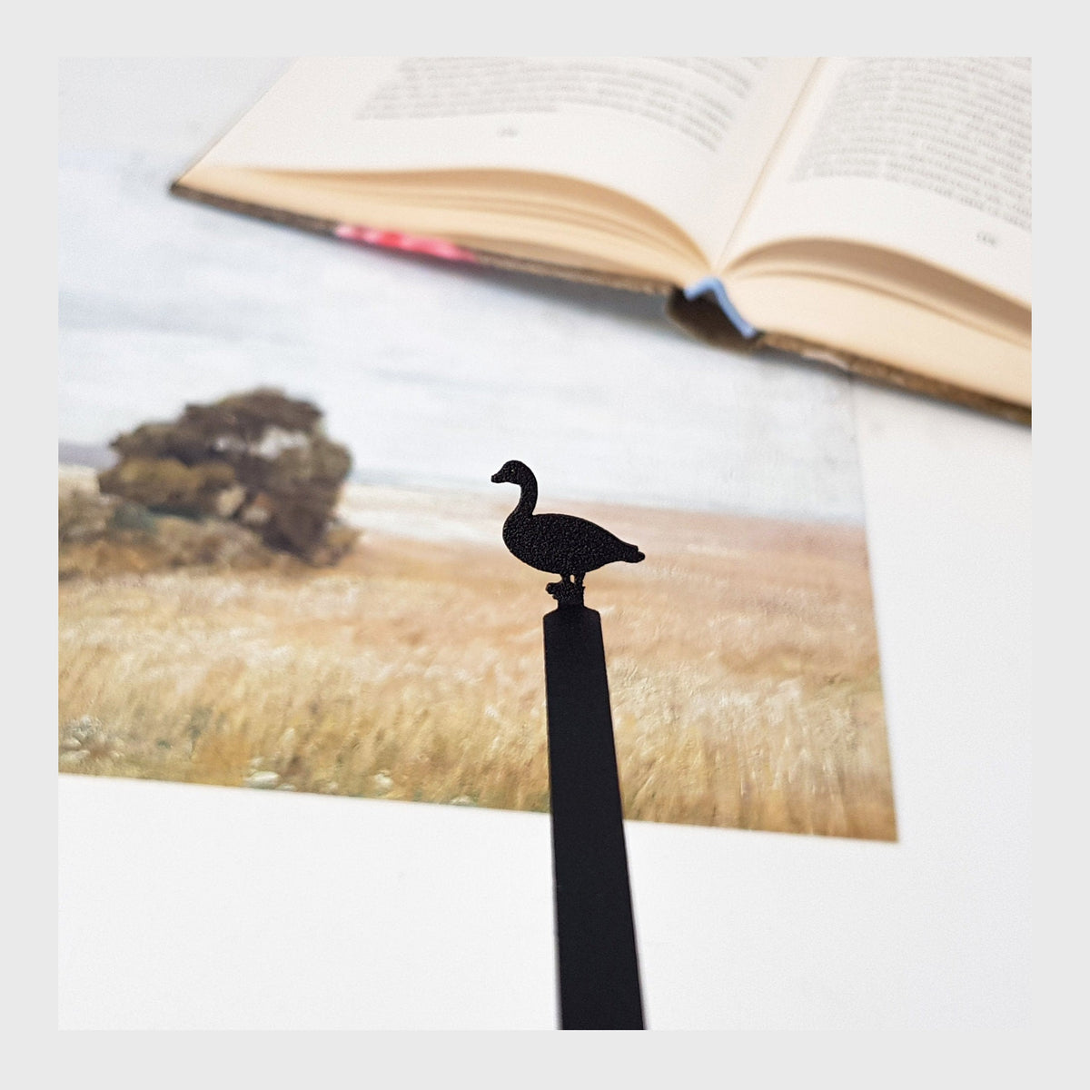 Goose metal bookmark marking a page in an illustrated book