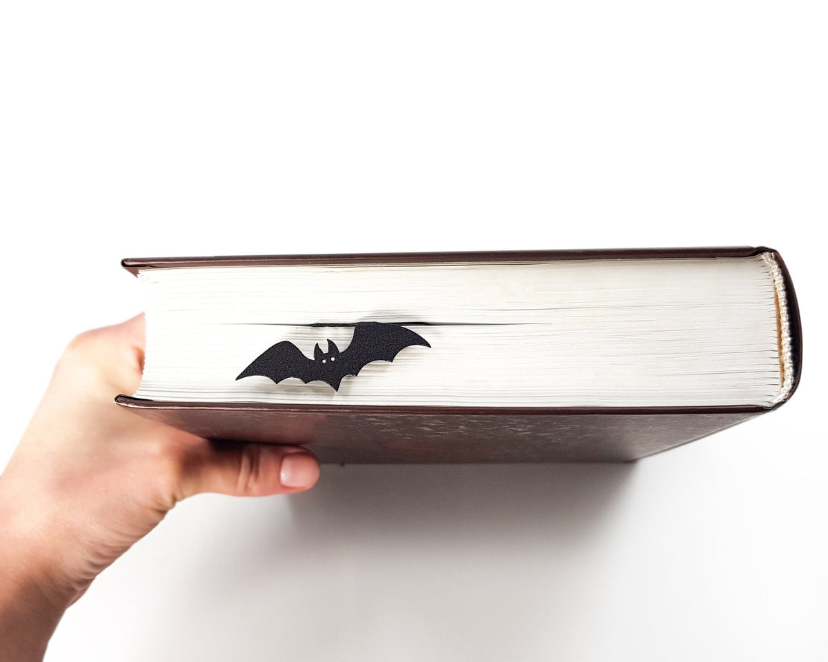 Gothic Coffin in My Book metal bookmark held in a hand above an open book