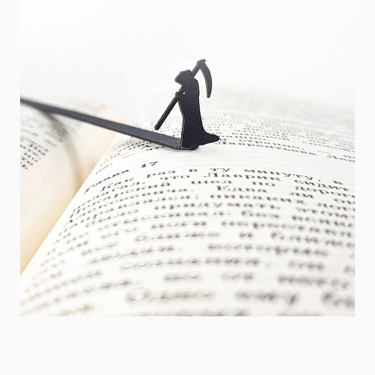 Grim Reaper metal bookmark resting on the pages of an open book