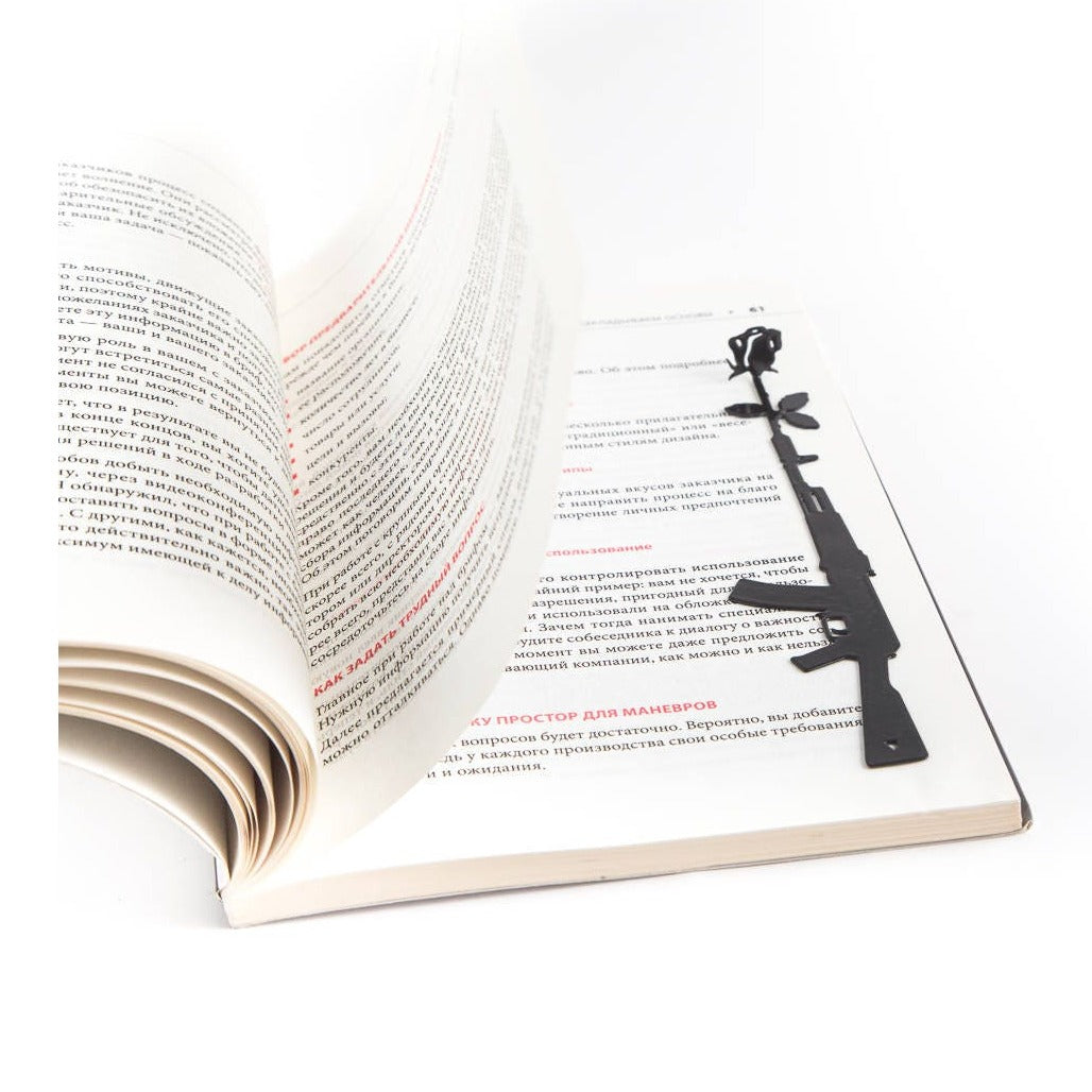 Gun with a Flower metal bookmark resting on the pages of an open book