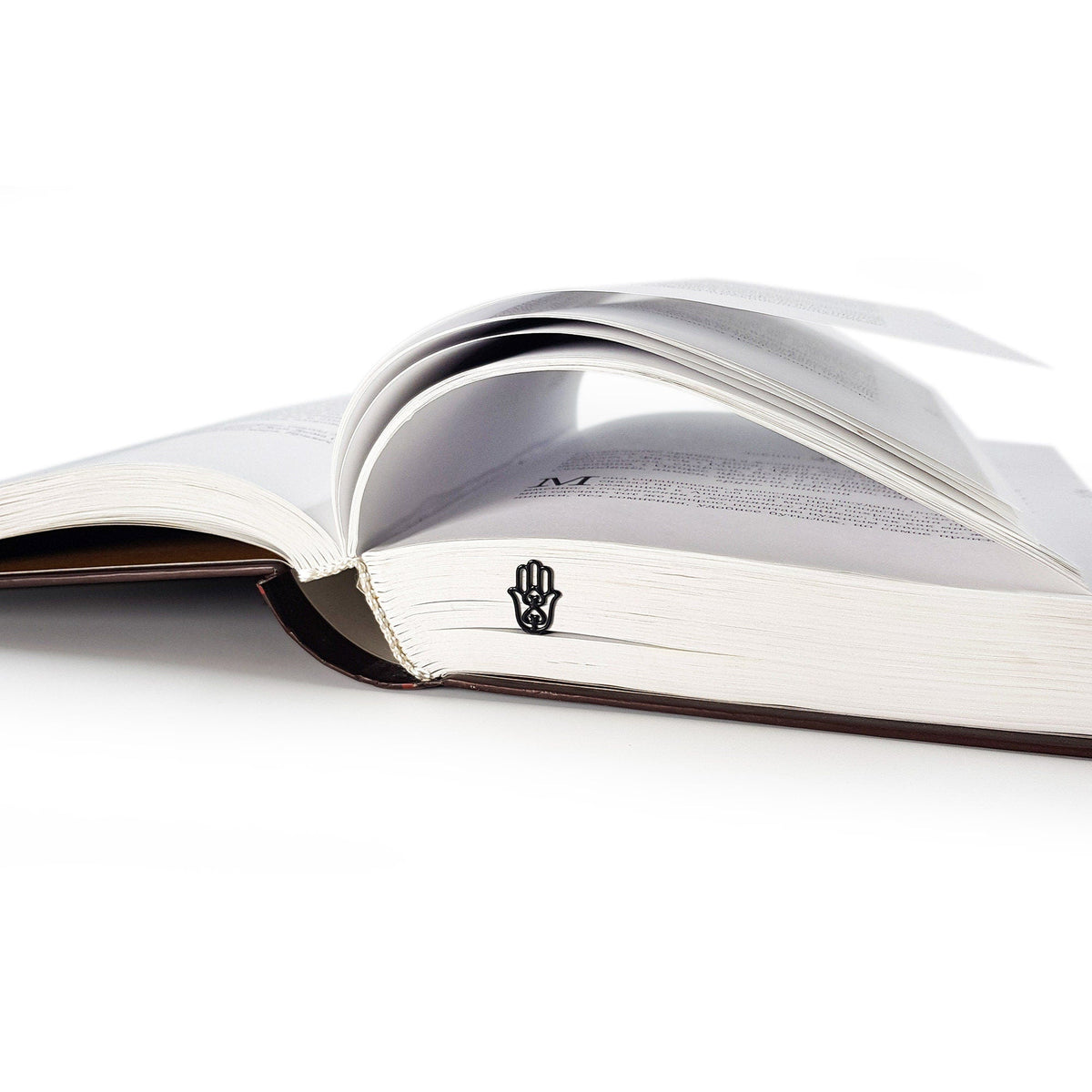 Hamsa metal bookmark set into the gutter of an open book