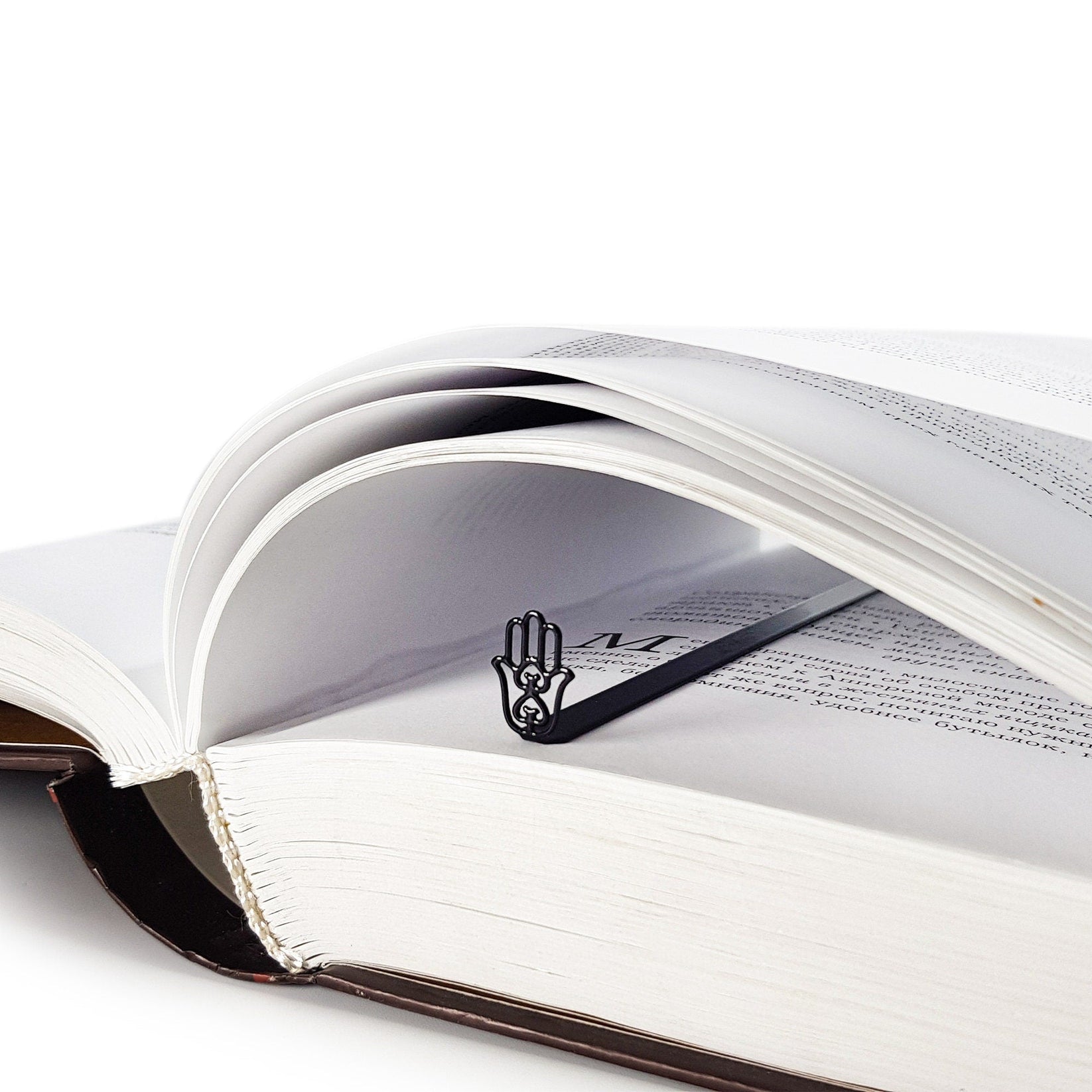 Hamsa metal bookmark resting on the pages of an open book