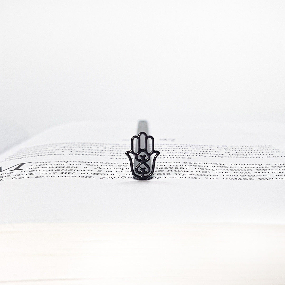 Hamsa metal bookmark lying across the pages of an open book