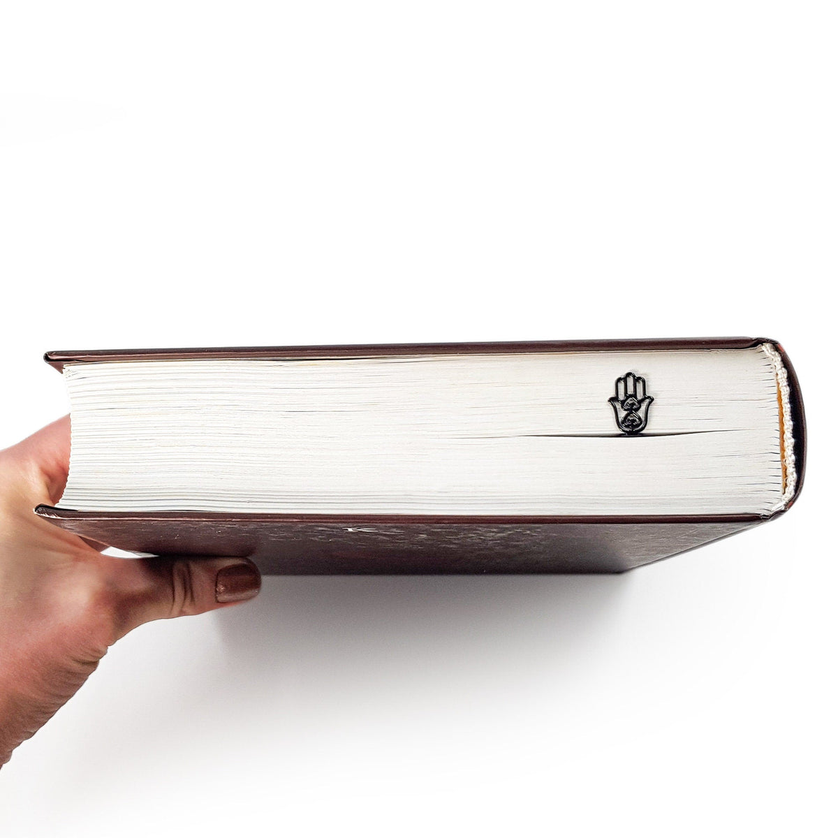 Hamsa metal bookmark in a closed book, only its top showing above the pages