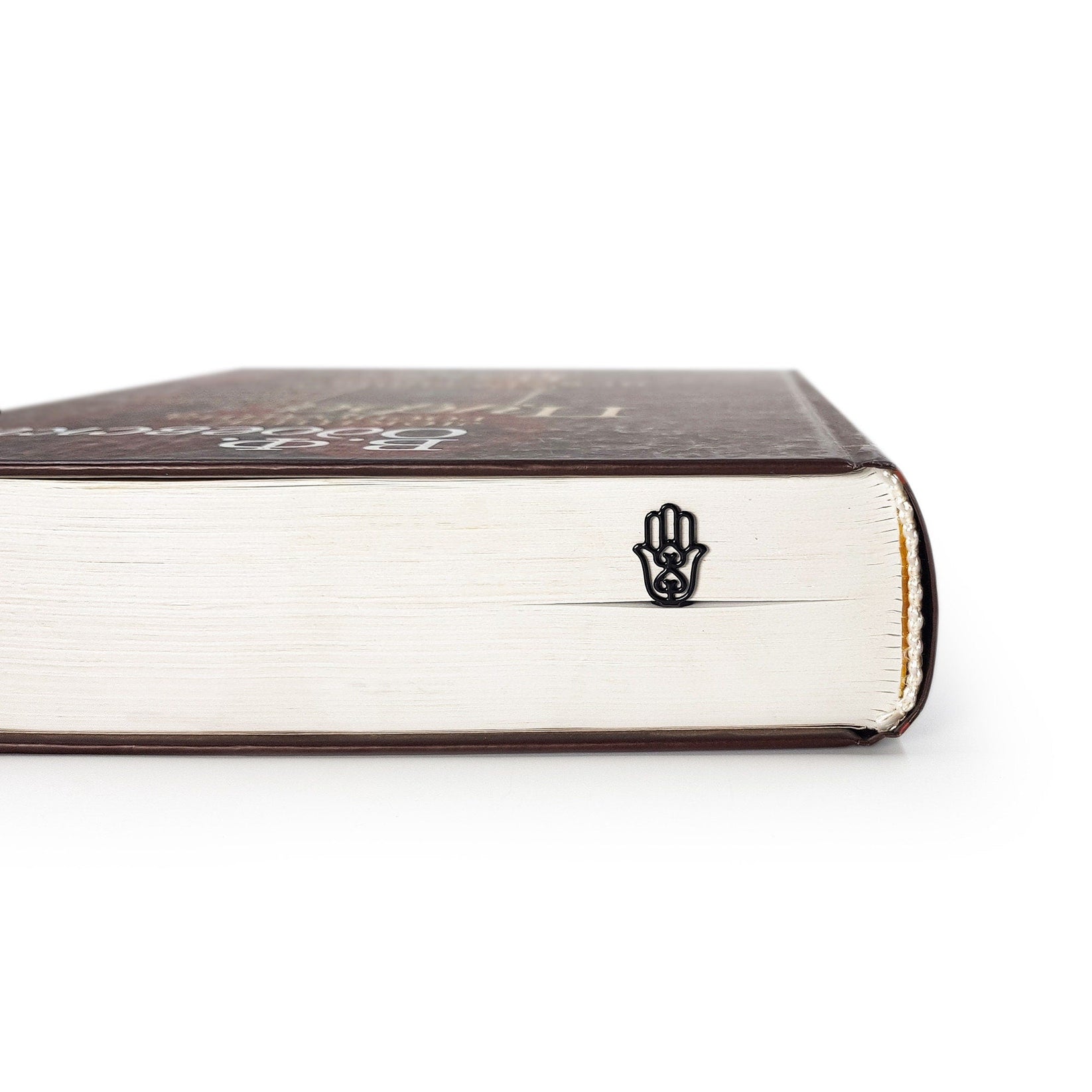 Hamsa metal bookmark seen from the edge of a closed book