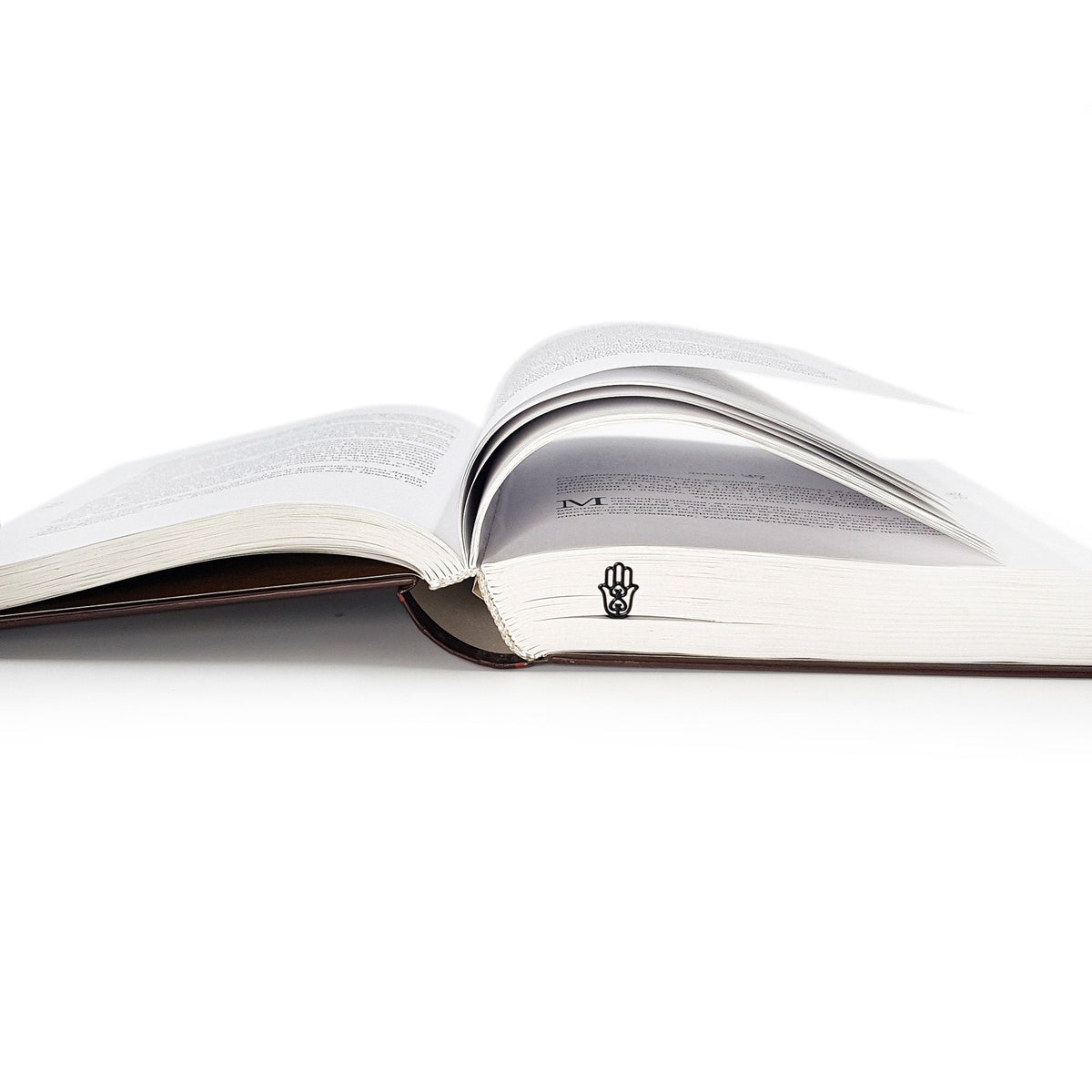 Hamsa metal bookmark marking a page in an open book