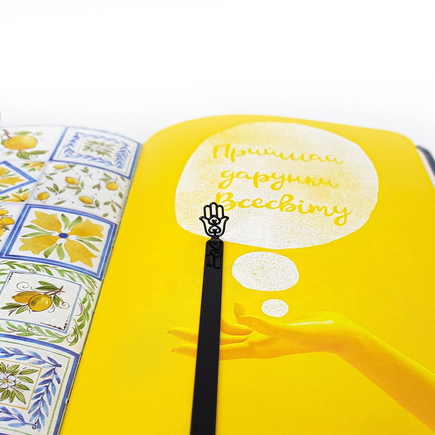 Hamsa metal bookmark marking a page in an illustrated book
