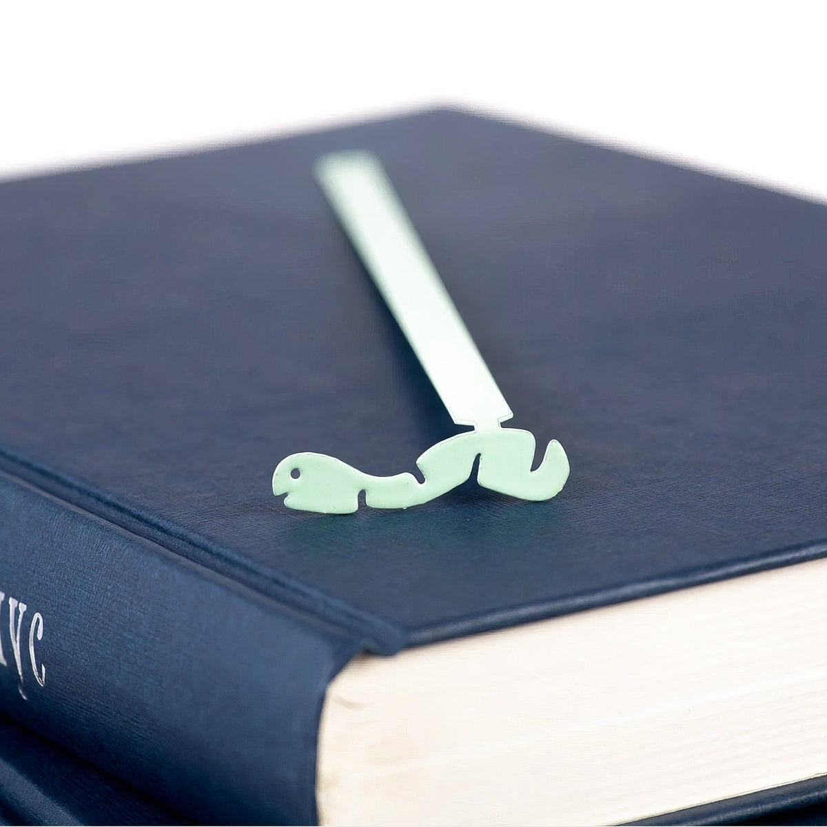 Happy metal bookmark in green in a closed book, only its top showing above the pages