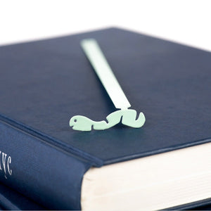 Happy metal bookmark in green in a closed book, only its top showing above the pages