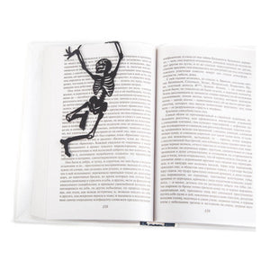 Happy Skeleton metal bookmark resting on the pages of an open book