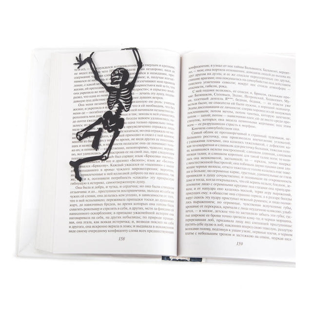 Happy Skeleton metal bookmark resting on the pages of an open book