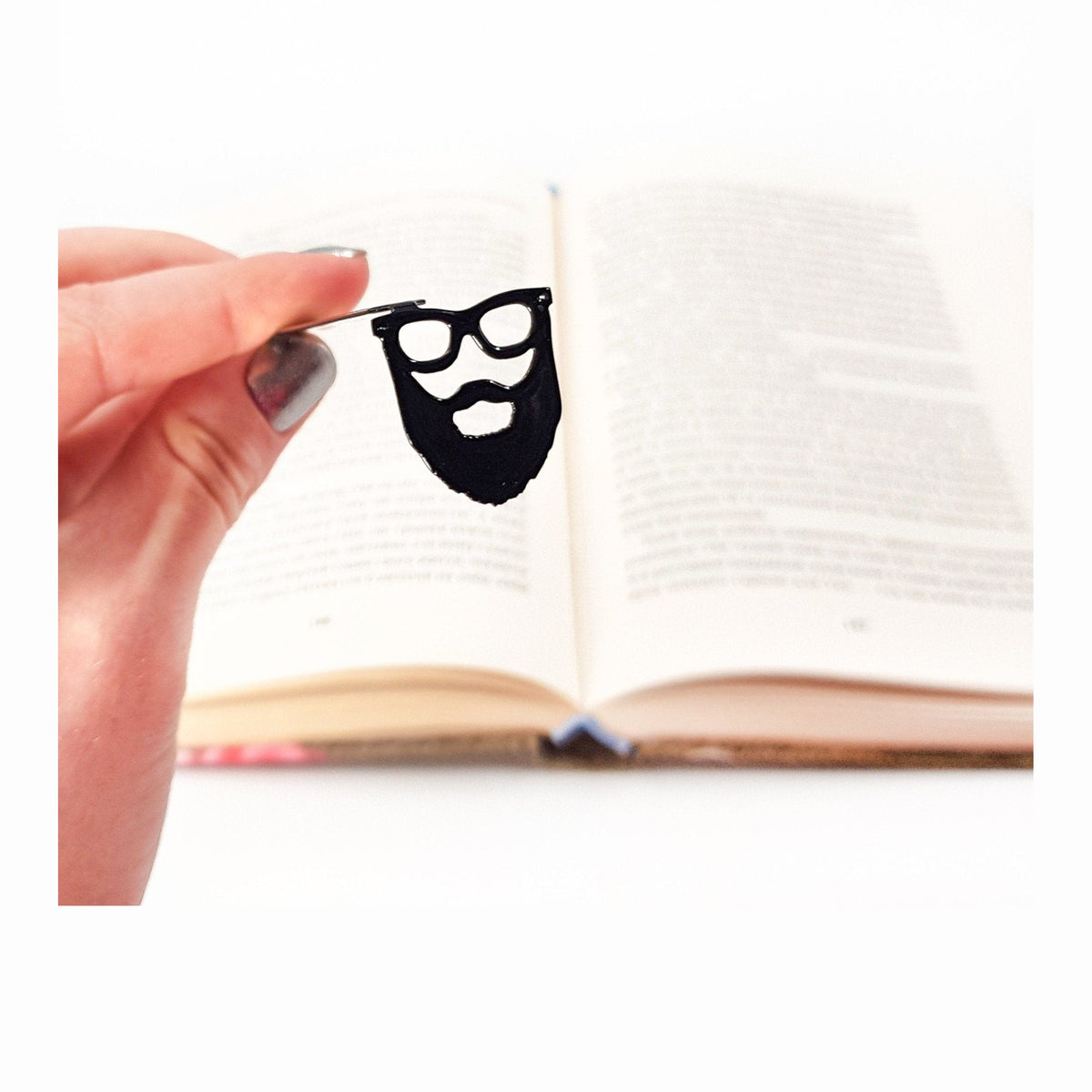 Hipster metal bookmark held in a hand above an open book