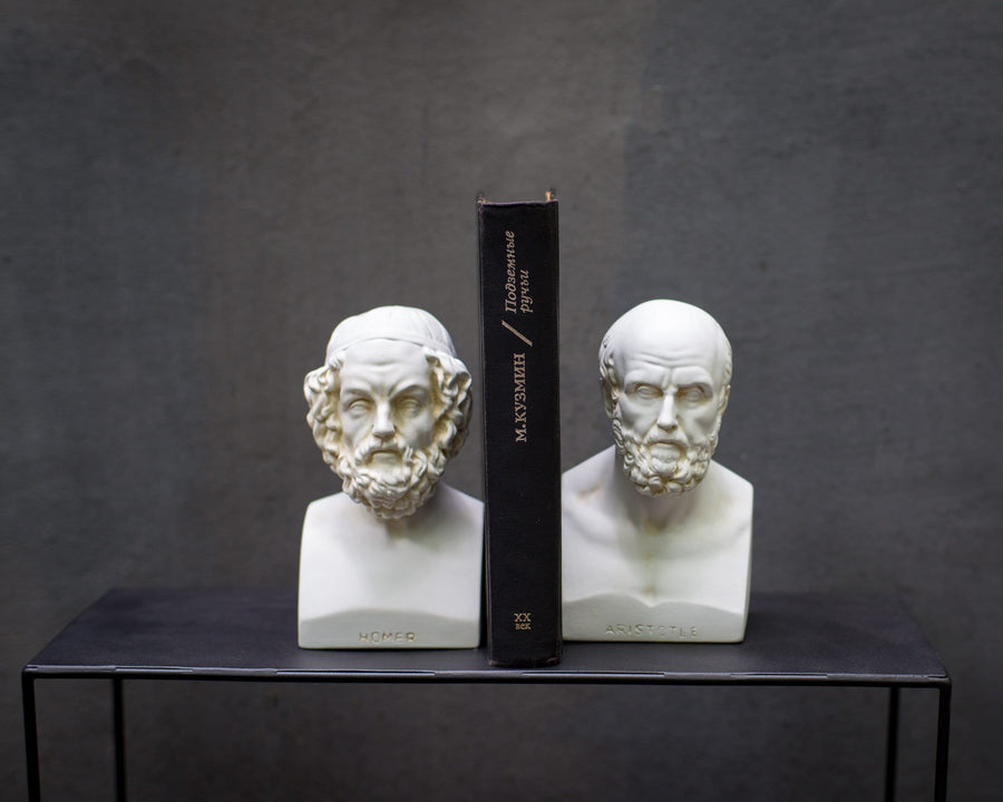 Plaster busts of Homer and Aristotle holding a black book between them