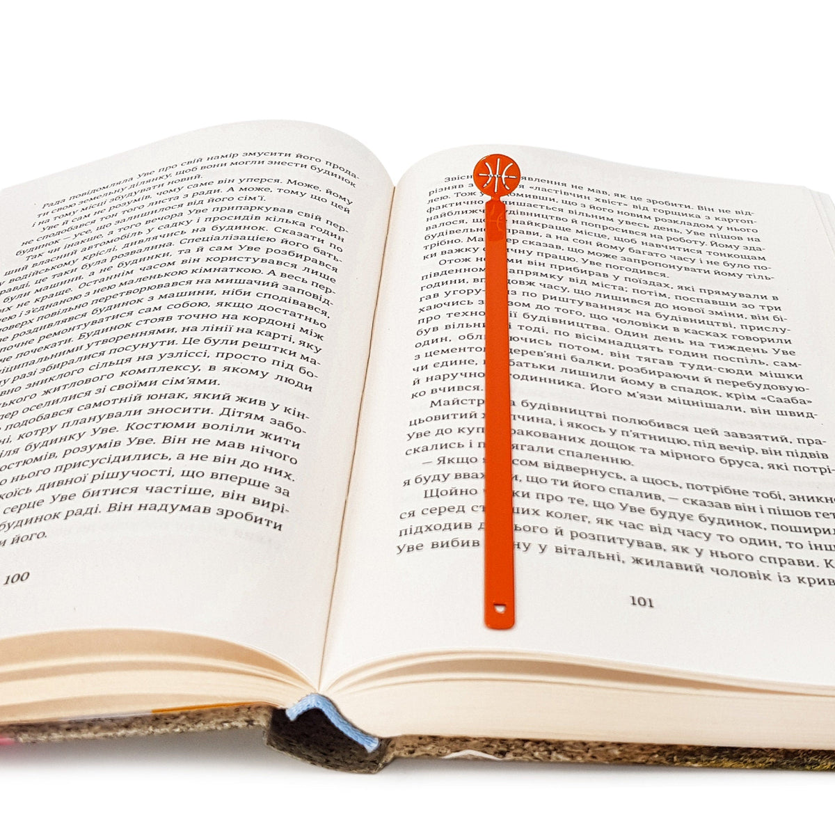 Hoop Dreams Mark metal bookmark in red marking a page in an open book