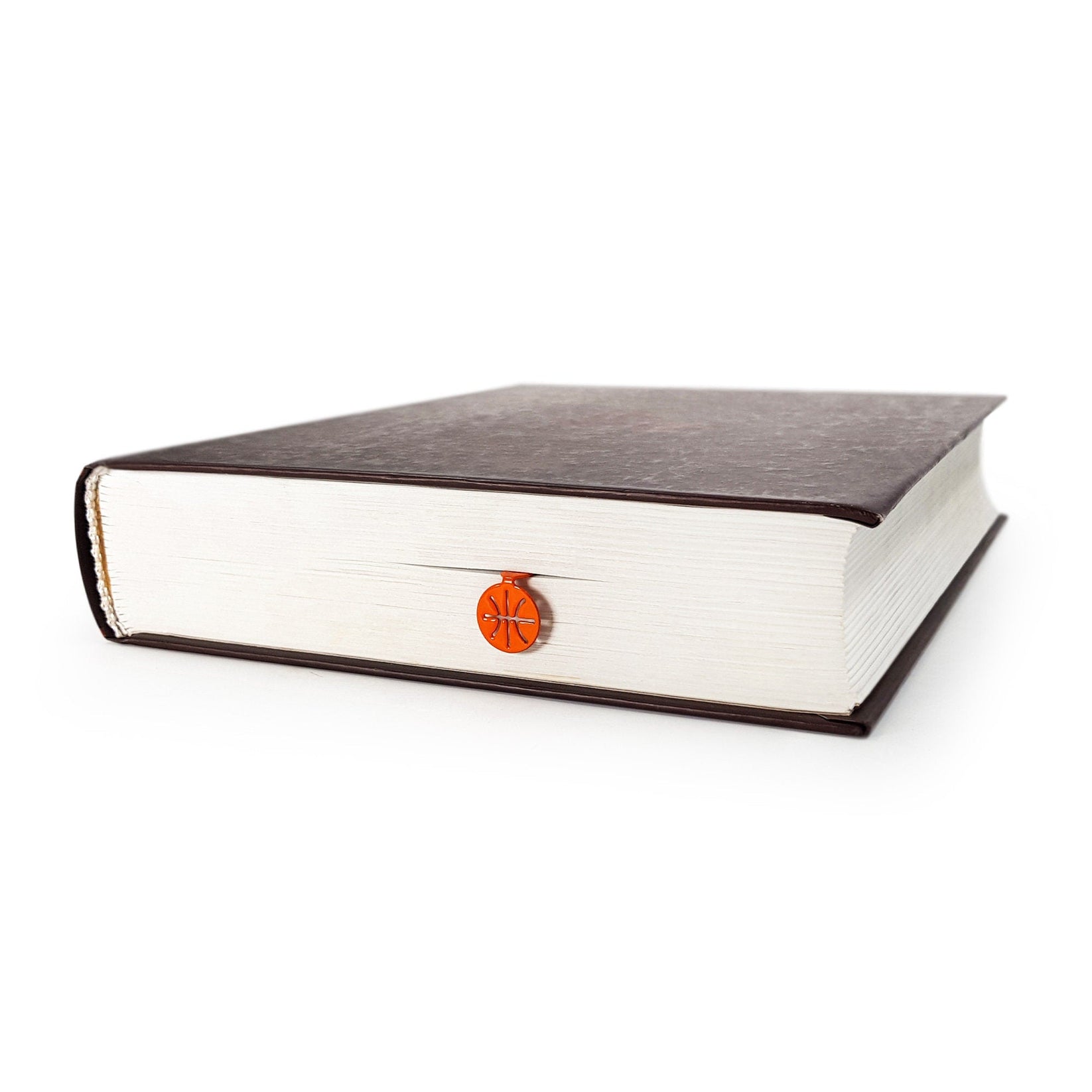 Hoop Dreams Mark metal bookmark in red seen from the edge of a closed book