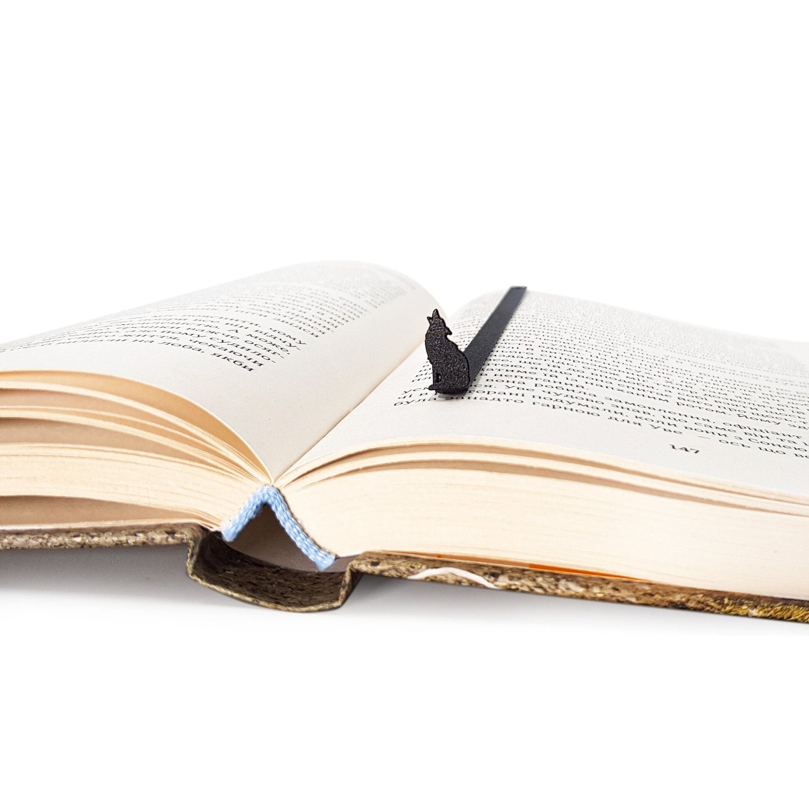 Howling Wolf metal bookmark resting on the pages of an open book