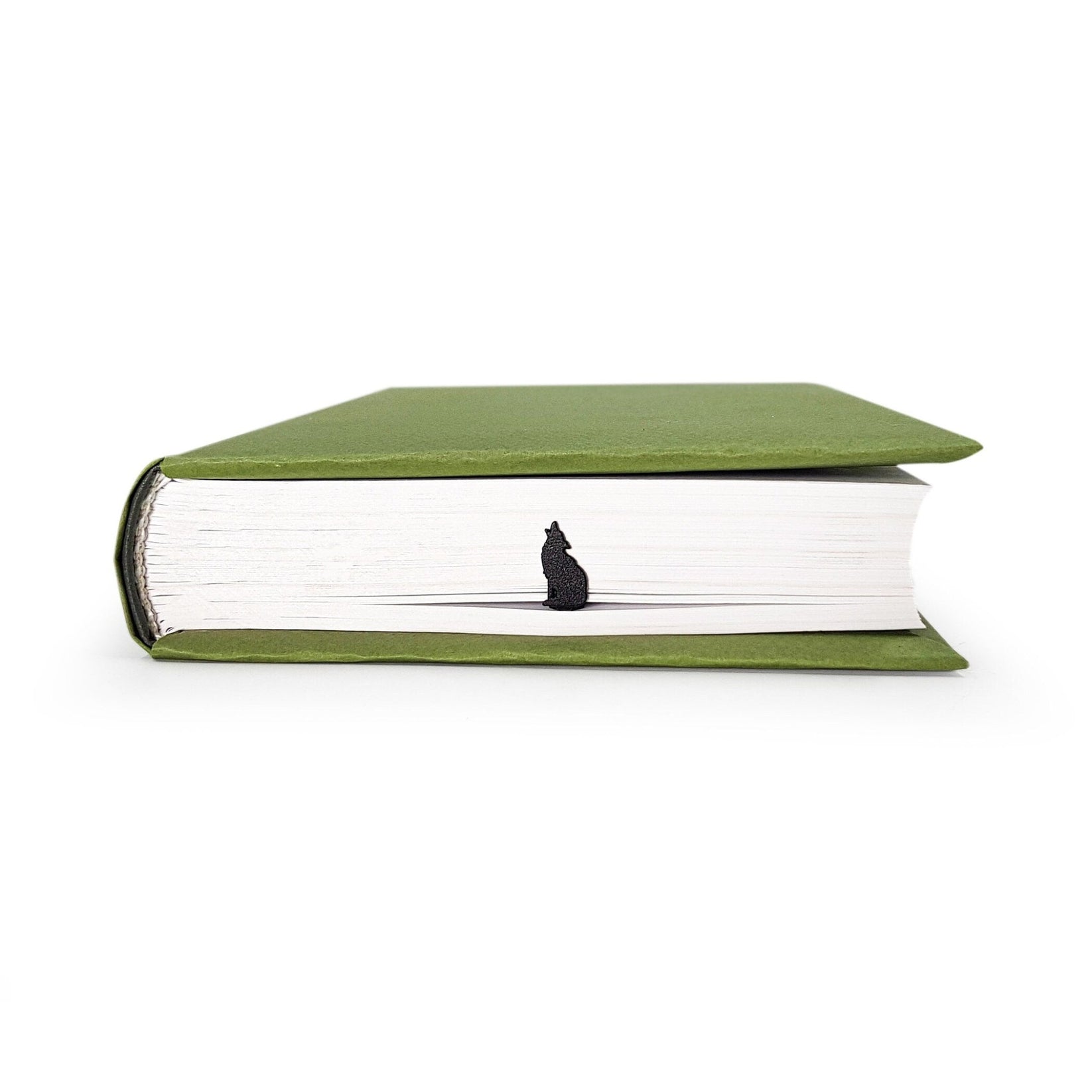 Howling Wolf metal bookmark in a closed book, only its top showing above the pages