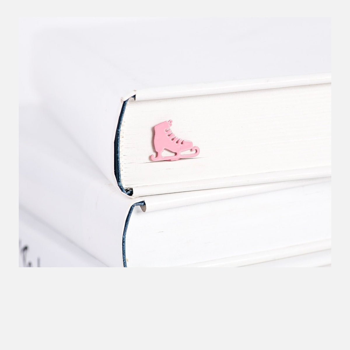 Ice Skates metal bookmark in red in a closed book, only its top showing above the pages
