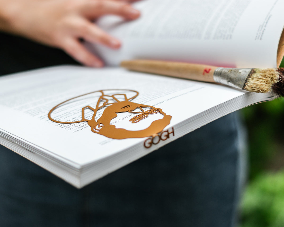 Van Gogh Portrait metal bookmark in gold held over a book, seen from the front