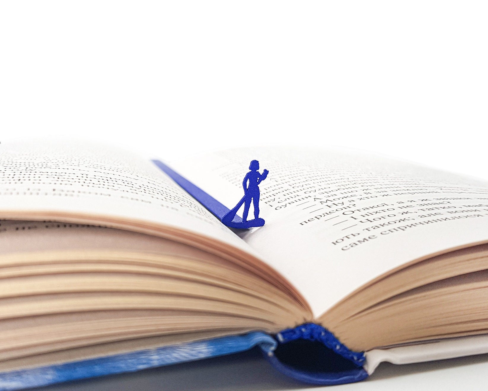 Surfer metal bookmark in blue lying across the pages of an open book
