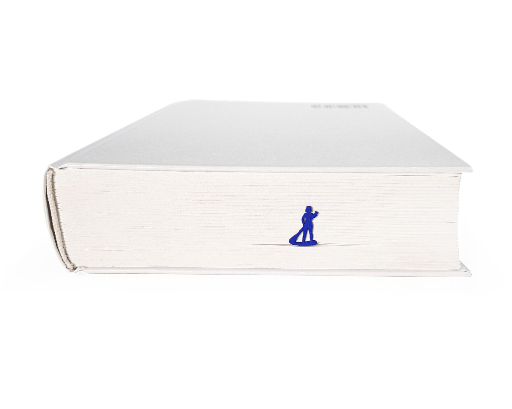 Surfer metal bookmark in blue seen from the edge of a closed book
