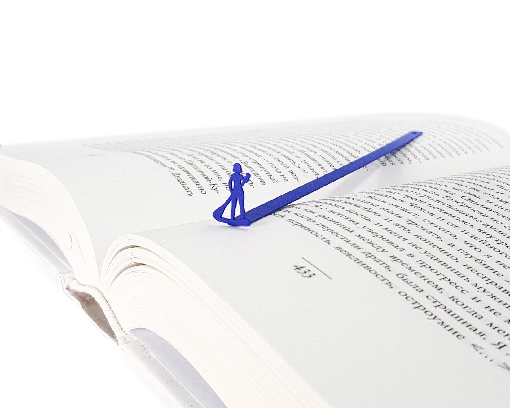 Surfer metal bookmark in blue set into the gutter of an open book
