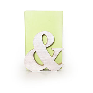 Natural wood ampersand bookend in front of a light green book, minimalist and modern typography decor for bookshelf or reading space.