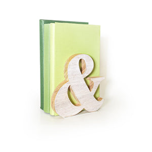 Wooden ampersand bookend holding green-toned books, natural minimalist shelf decor with typographic charm for home or office display.