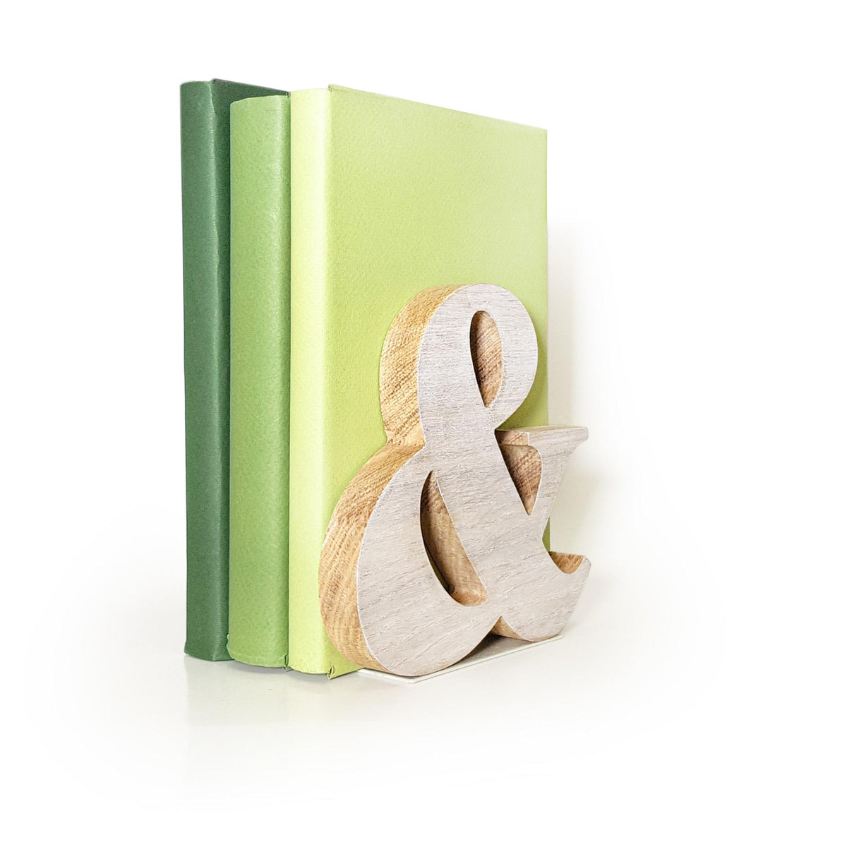 Minimalist wooden ampersand bookend propping up green books, handcrafted natural decor piece for modern shelves or reading corners.