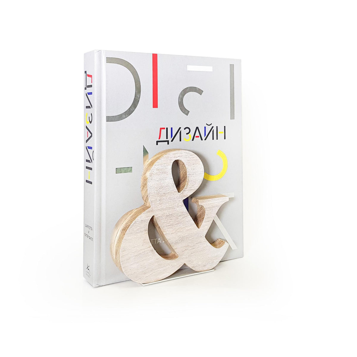 Wooden ampersand bookend in front of a modern design book with Cyrillic text, natural typographic shelf decor for creative home or office.