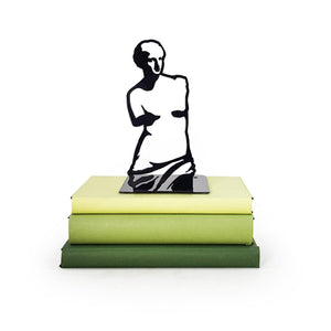 Artistic metal bookend shaped like Venus de Milo silhouette in black, displayed on stacked green books, minimalist and sculptural decor piece.