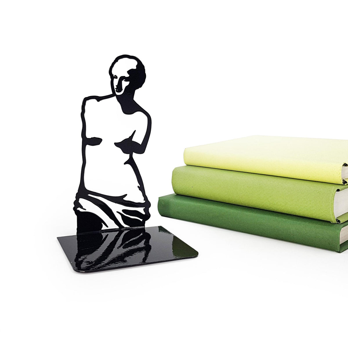 Black metal Venus de Milo bookend next to stacked green books, featuring a glossy finish and minimalist classical art silhouette design.