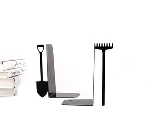 Side view of black metal bookends shaped like garden tools – a shovel and a rake – shown with stacked books. Sturdy and minimalist, ideal for gardeners or anyone who loves playful, nature-inspired shelf decor.