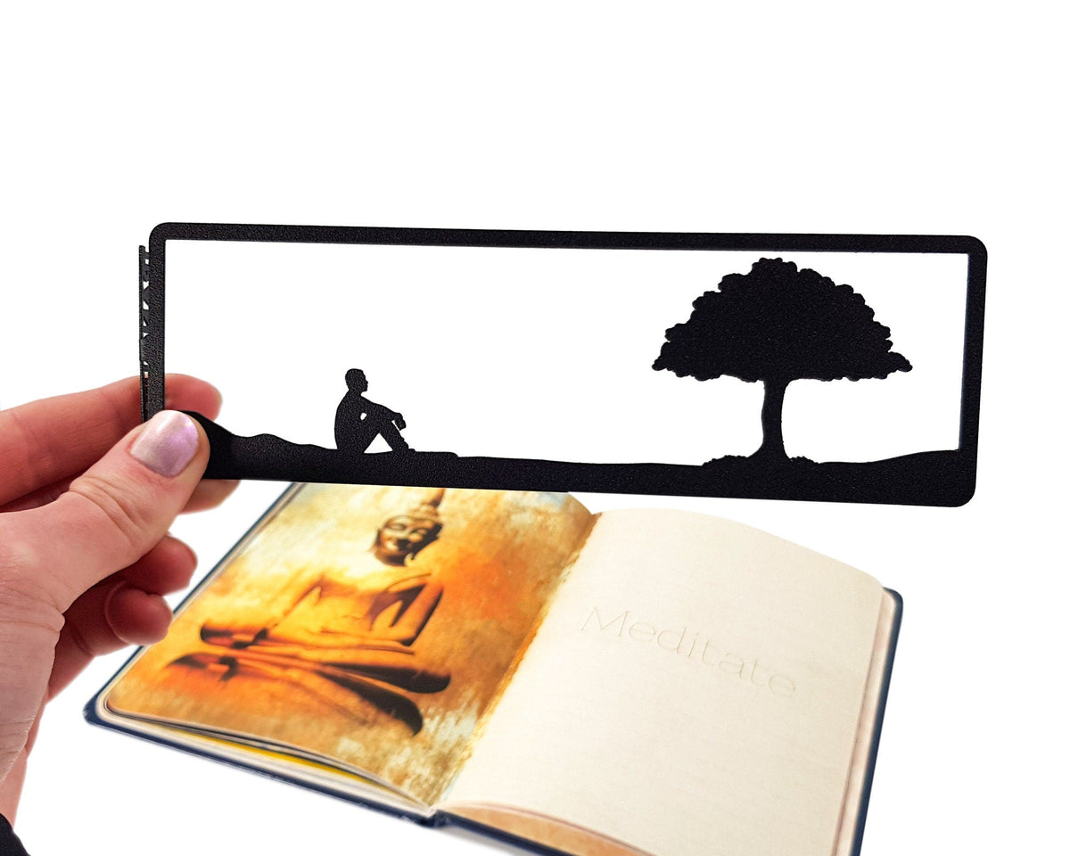 Inspirational Tranquility metal bookmark held in a hand above an open book