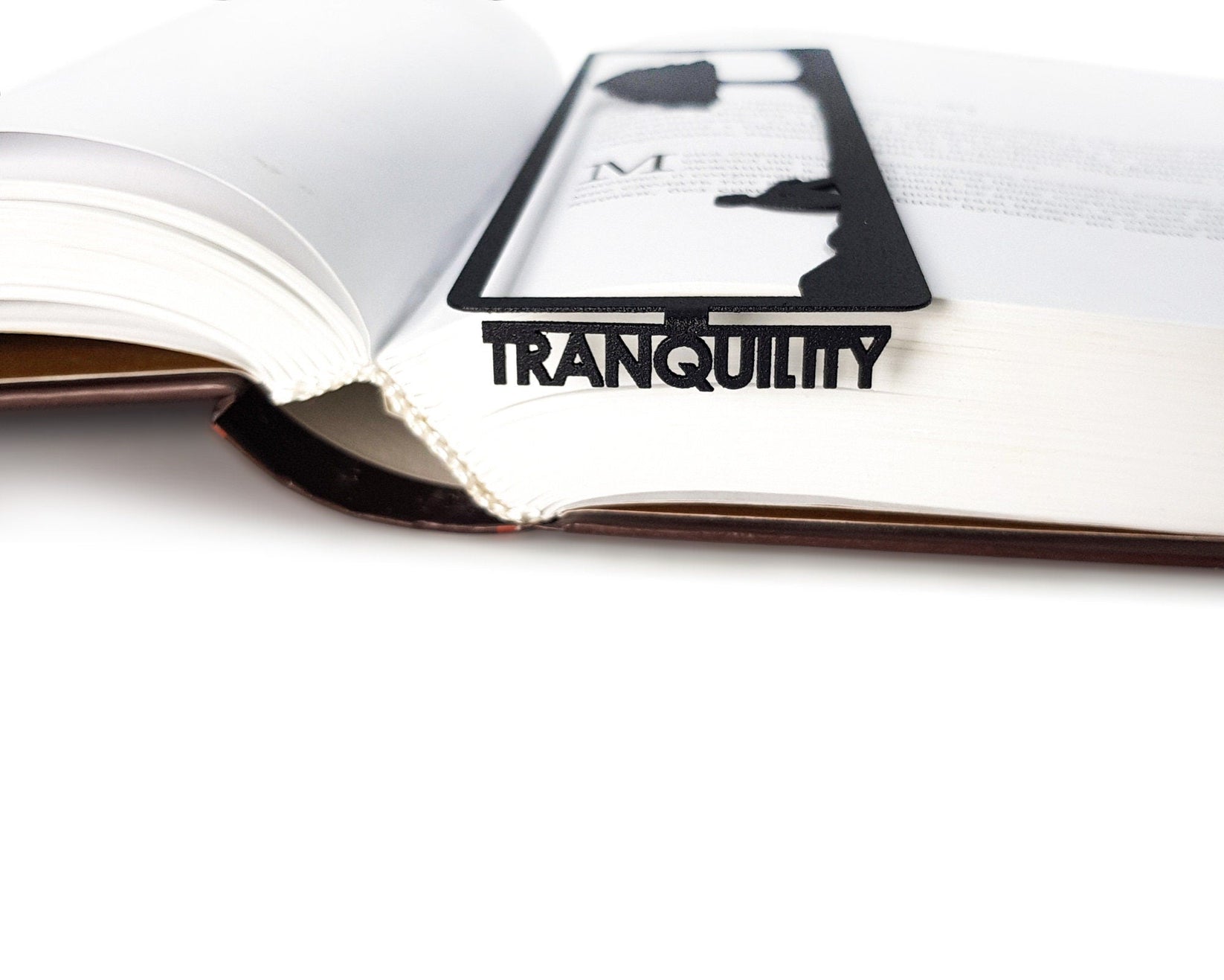 Inspirational Tranquility metal bookmark lying across the pages of an open book