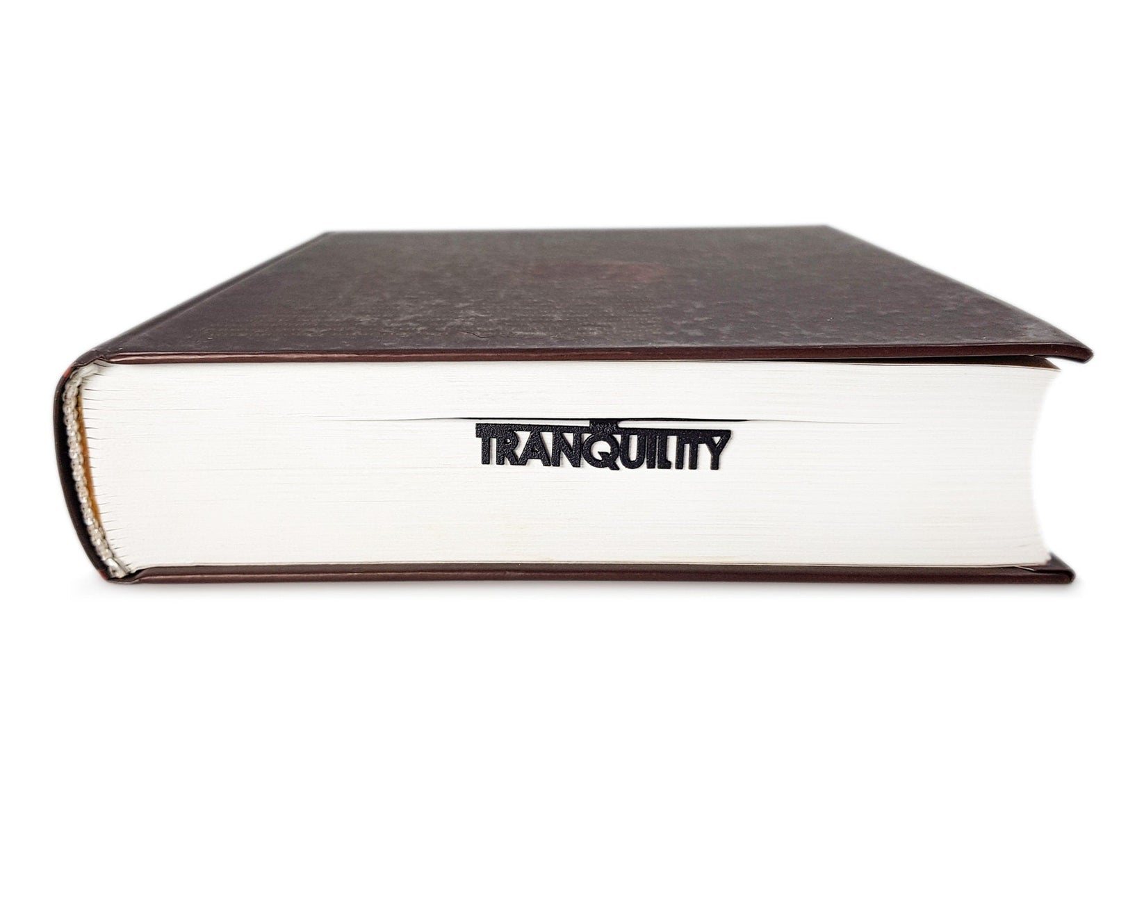 Inspirational Tranquility metal bookmark in a closed book, only its top showing above the pages