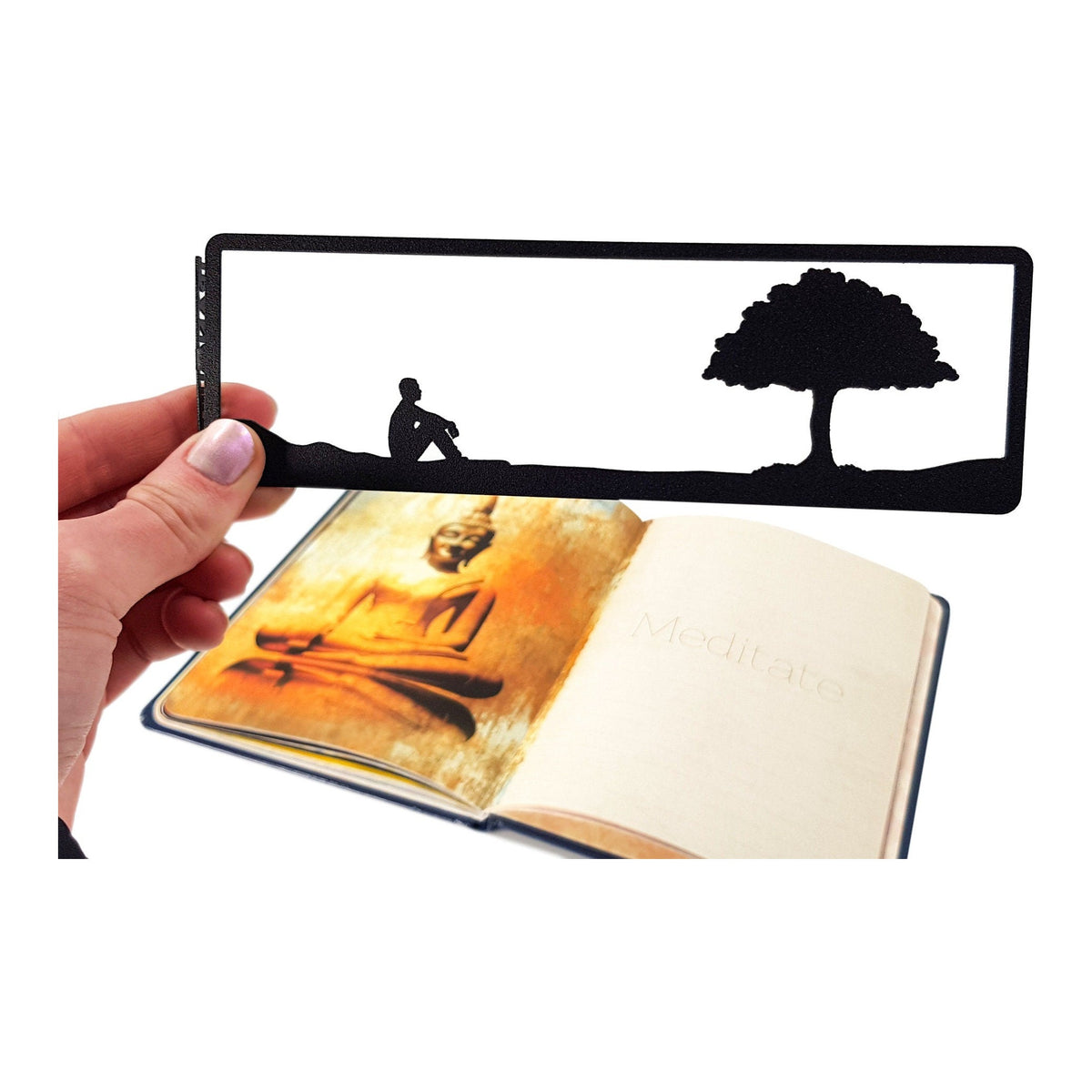 Inspirational Tranquility metal bookmark held in a hand above an open book