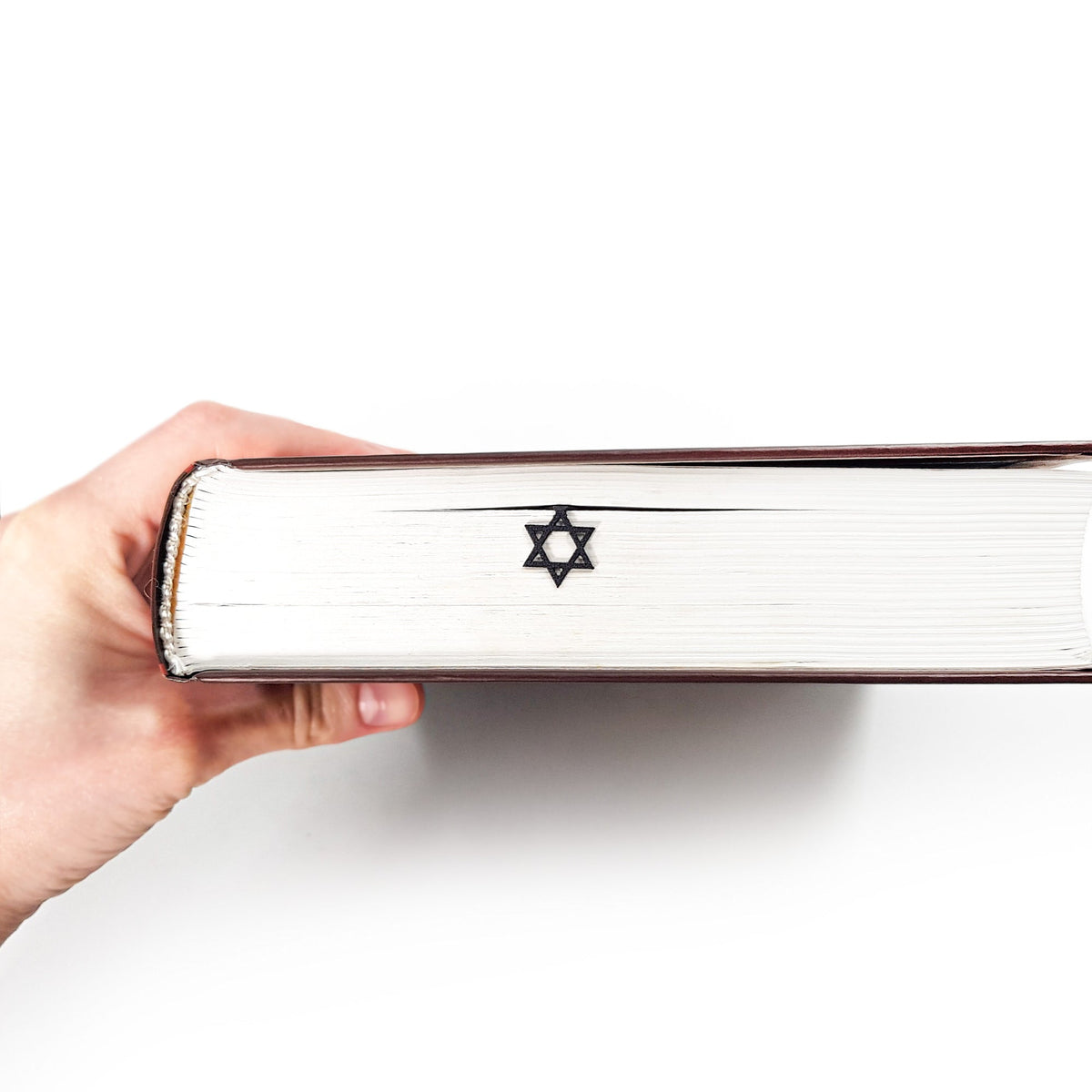 Judaical Star of David metal bookmark held up beside an open book