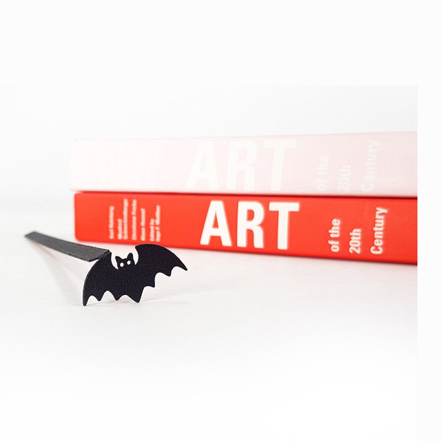 Kitti Bat metal bookmark in a closed book, only its top showing above the pages