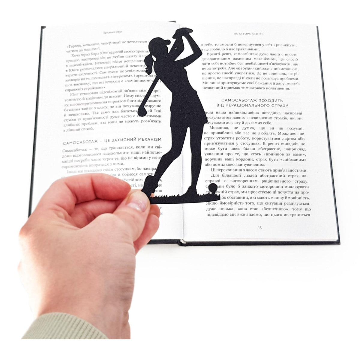 Lady Golf Player metal bookmark held in a hand above an open book