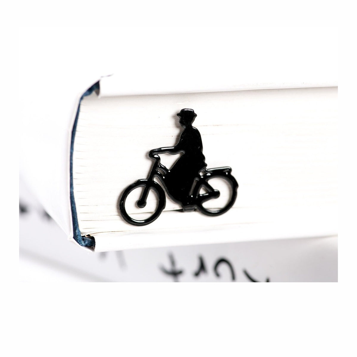 Lady on the Bike metal bookmark resting on the pages of an open book